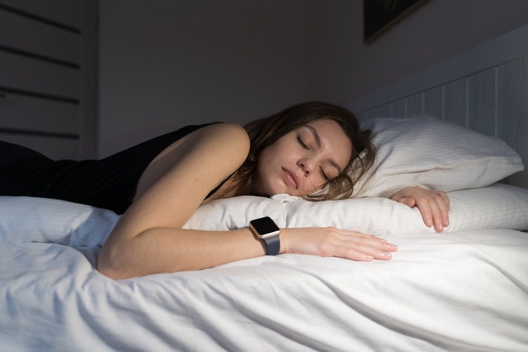 Nainen nukkuu sängyssä Apple Watch ranteessaan.